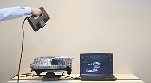 Person using a 3D scanner on an object with a laptop displaying the scan.