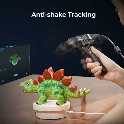 Hand using a device to track a green toy dinosaur on a rotating stand.