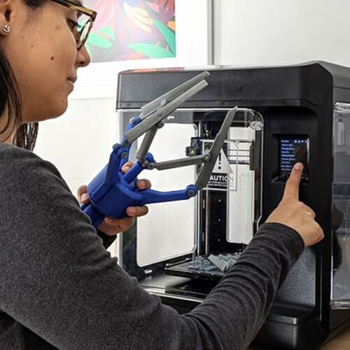 Person operating a 3D printer with a robotic arm.