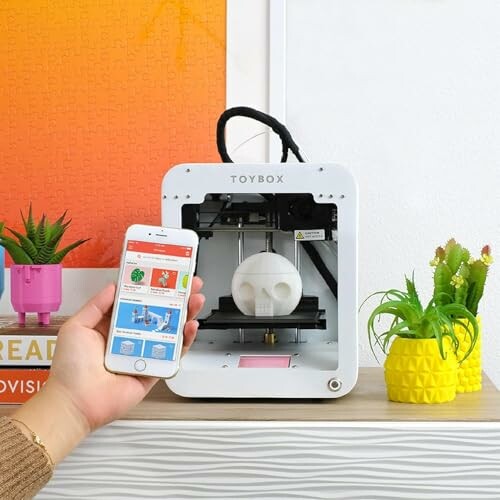 Toybox 3D printer with a smartphone app displaying designs.